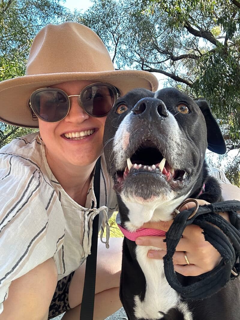 Armağan smiling beside her dog, Qara, outdoors